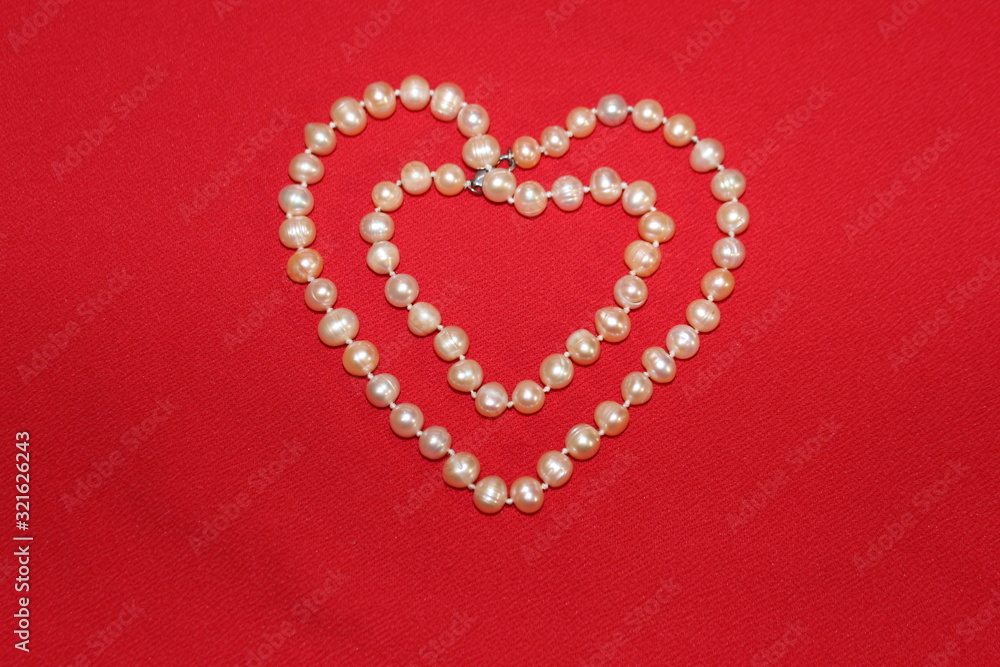 Heart made of pearls on a red background. Heart made of beads. Heart for valentines day.