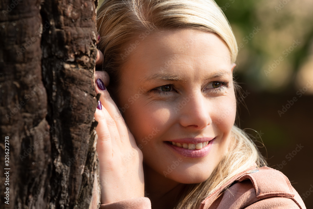 Portrait of a blonde woman next a tree with textured bark Portrait of a blonde woman next a tree with textured bark