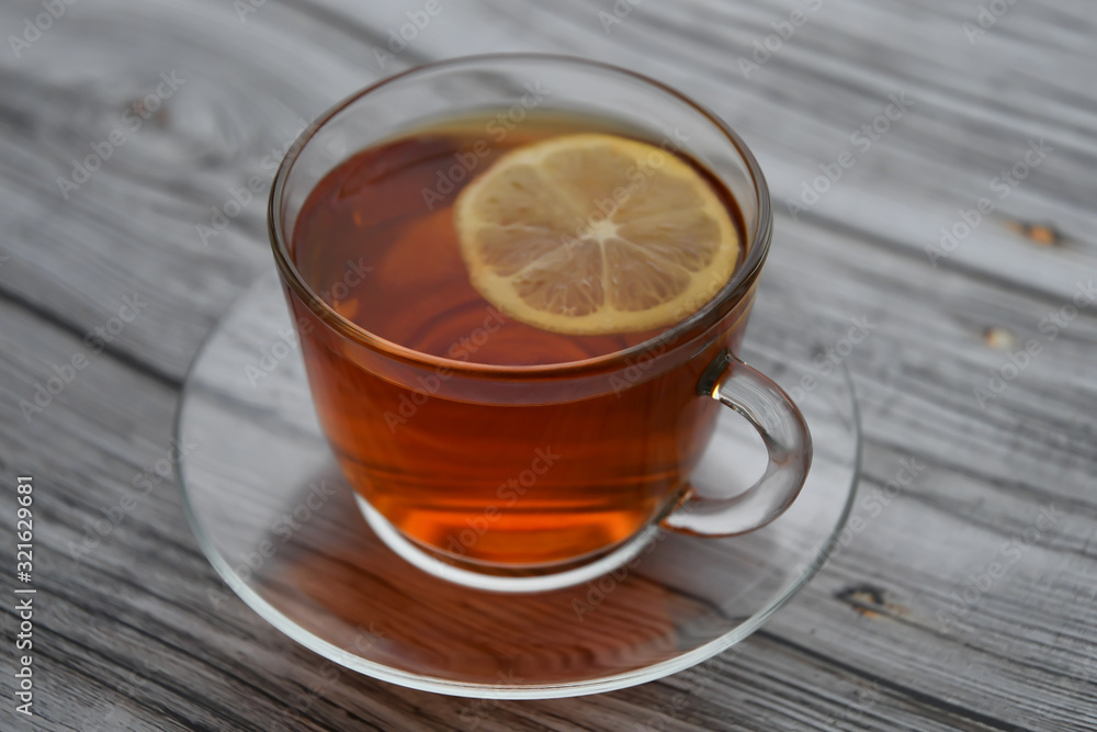 A cup of black tea with lemon on a wooden table