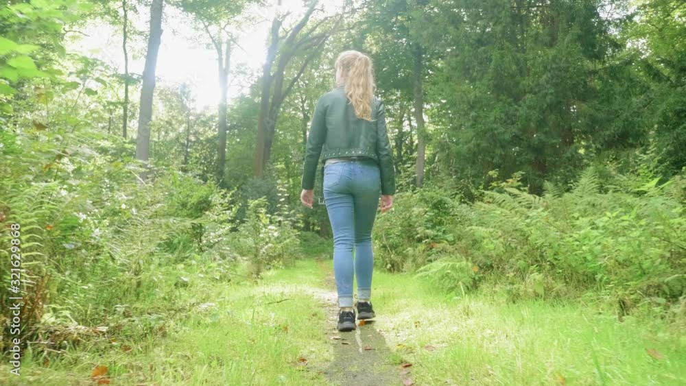 View from low behind girl walking on nature trail in sunlight, tracking View from low behind girl walking on nature trail in sunlight, tracking