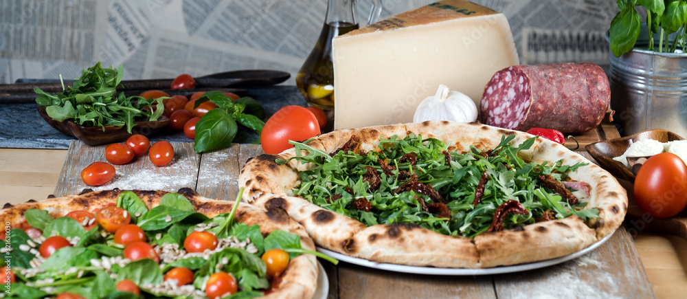 Fototapeta premium Italian style pizza, fresh arugula and cherry tomatoes prepared on wooden boards
