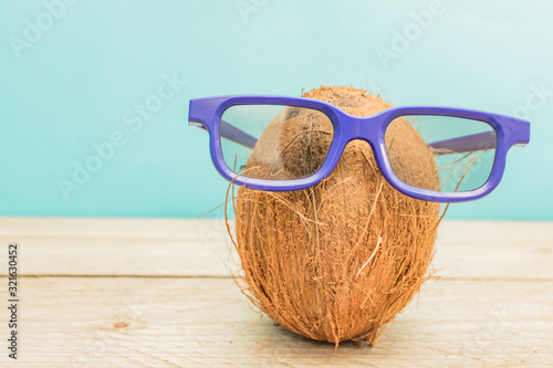 A cocnut wearing 3D glasses on blue background. Summer and trave concept