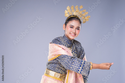 A beautiful Malaysian traditional female dancer with a charming smile performing a cultural dance steps in a traditional outfit. Half length isolated in grey. photo