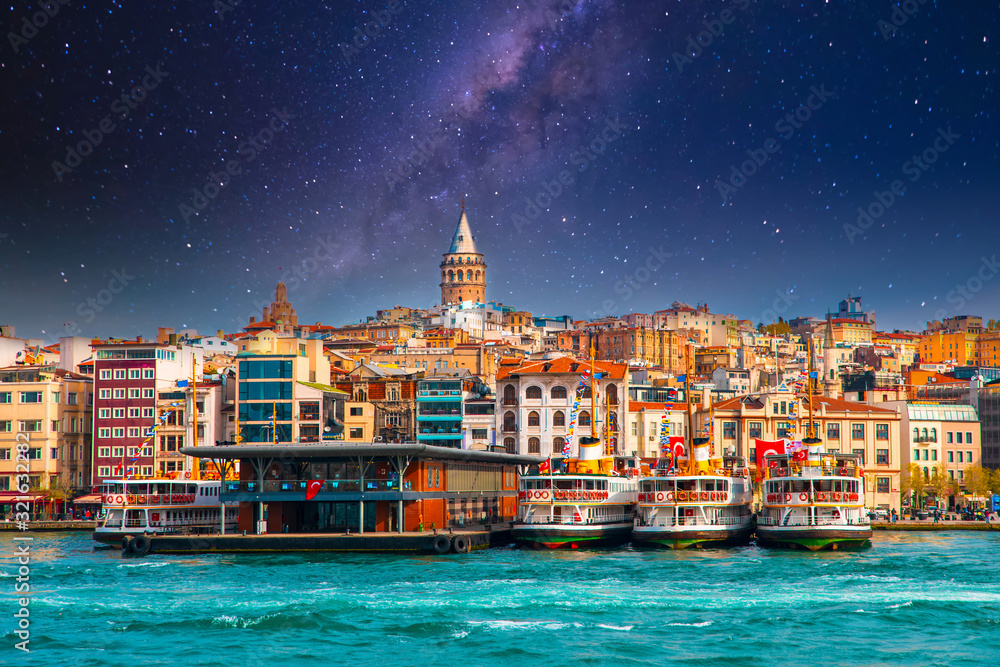 Naklejka premium Wieża Galata w Stambule w Turcji. Widok na miasto Stambuł w Turcji z Bosfor, mewy i łodzie na jasne niebo i zachód słońca lub w nocy.