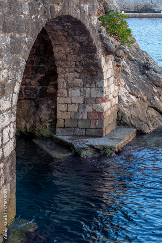 Ancient brick arch under the fortress with bottom beneath the water in Old town Dubrovnik