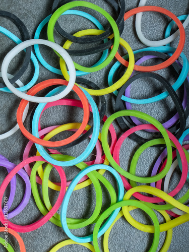 Multiple colored rubberbands in a pile on a gray textured background