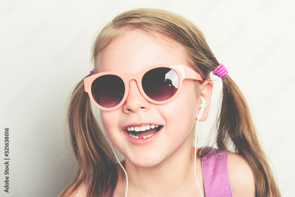 little happy girl in sunglasses and with headphones laughing - studio shot little happy girl in sunglasses and with headphones laughing - studio shot