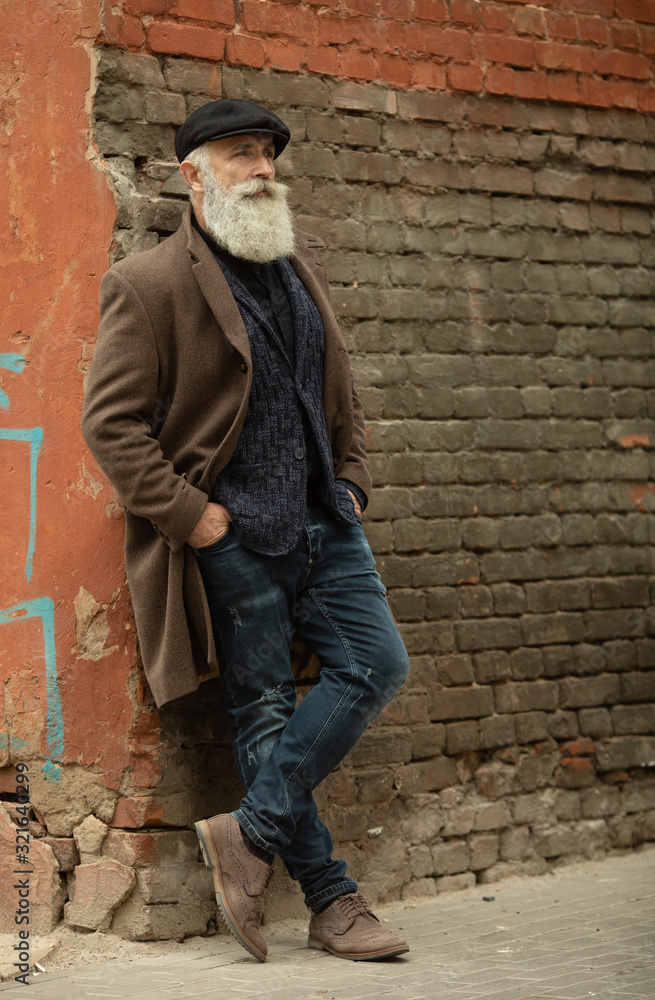 Fashionable senior man with gray hair and beard is outdoors on the street. Fashionable senior man with gray hair and beard is outdoors on the street.