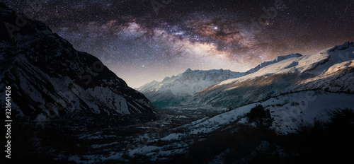 Night panorama of Milky Way over the snowy mountains in winter.
