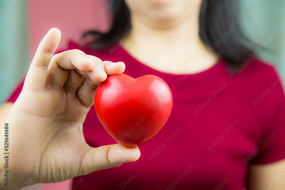 A red heart shaped balloon in the woman's hand For the concept of the day of love and happiness, Valentine's Day, February 14. A red heart shaped balloon in the woman's hand For the concept of the day of love and happiness, Valentine's Day, February 14.