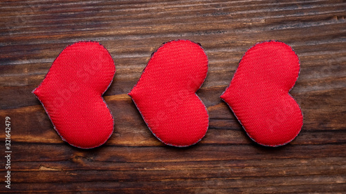 Handmade red hearts on a dark wooden background arranged in a row_