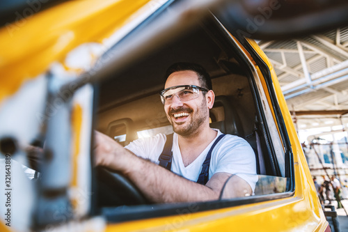 Smiling handsome unshaven worker driving vehicle on construction site. © dusanpetkovic1