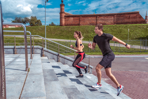 man and woman run in summer training session in city. Jogging an active lifestyle, sports couple. Free space for copy text. Step background lawn. Sportswear, jumping run.
