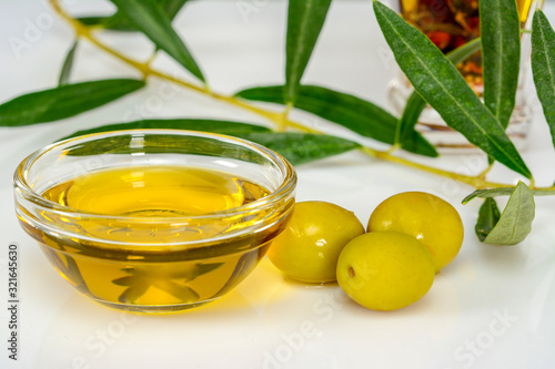 Olive oil. Glass transparent bowl with virgin olive oil and pitted olives nearby. Macro close-up, high resolution.