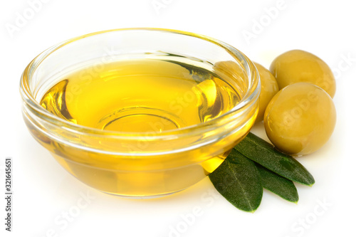 Olive oil. Greek olive oil in glass transparent bowl with three green olives and leaves. Close-up, Isolated on white background.