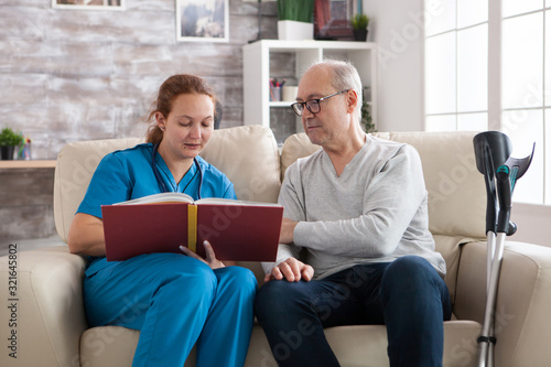 Young female doctor reading a book for old man