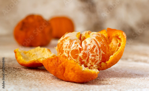 Partially peeled mandarin, peels and whole mandarins on a table. © Ulya
