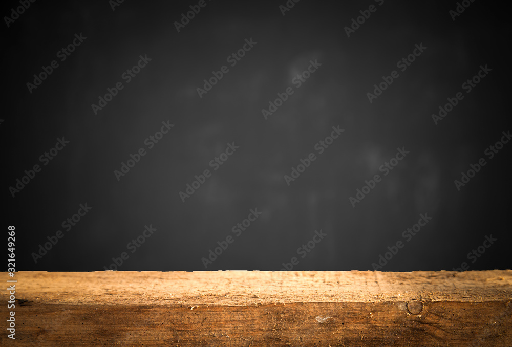 Empty wooden table on a background of dark blurred wall, empty space for product above Empty wooden table on a background of dark blurred wall, empty space for product above