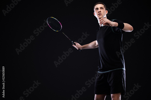 Badminton player in sportswear with racket and shuttlecock on black background. Individual sports. Sports recreation. © Mike Orlov