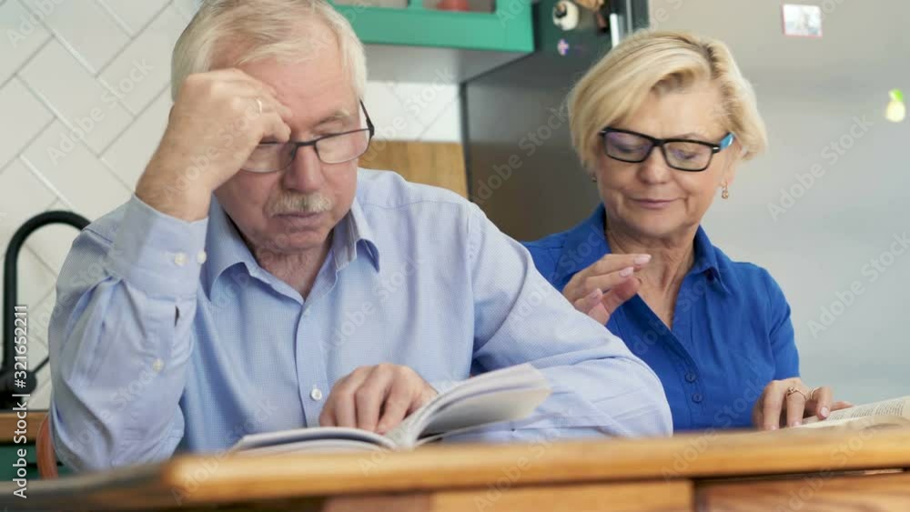 Middle aged couple reading books at home, man getting sleepy. Middle aged couple reading books at home, man getting sleepy.