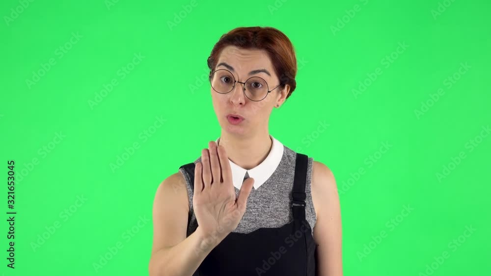Portrait of funny girl in round glasses strictly gesturing with hands shape meaning denial saying NO. Green screen Portrait of funny girl in round glasses strictly gesturing with hands shape meaning denial saying NO. Green screen