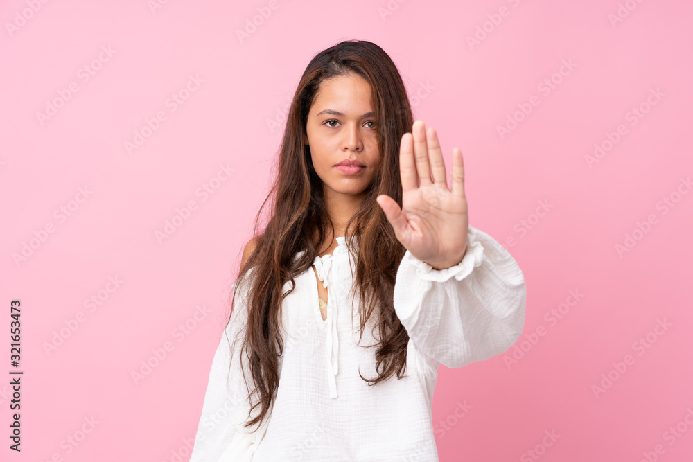 Young Brazilian girl over isolated pink background making stop gesture Young Brazilian girl over isolated pink background making stop gesture