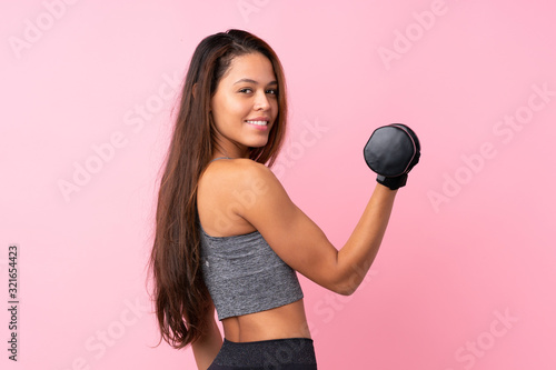 Young sport Brazilian girl over isolated pink background making weightlifting
