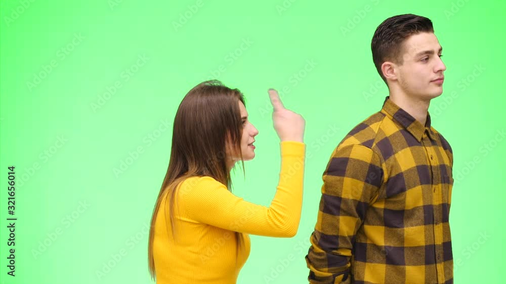Young woman is argueing with young man, being on green background, isolated. Copy space. 4K. Young woman is argueing with young man, being on green background, isolated. Copy space. 4K.