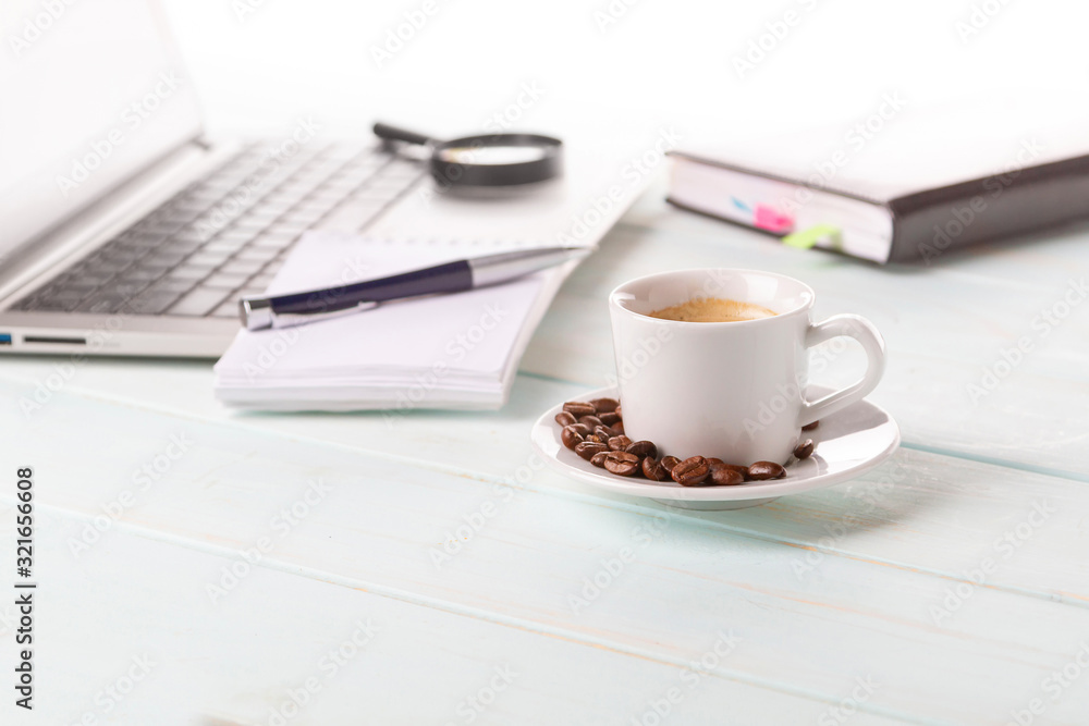 A cup of good coffee at work. Notebook, pen, laptop, calculator, financial documents, a cup of hot cappuccino on the table. Coffee grains.Magnifying glass. A cup of good coffee at work. Notebook, pen, laptop, calculator, financial documents, a cup of hot cappuccino on the table. Coffee grains.Magnifying glass.