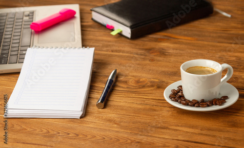 A cup of good coffee helps in working with documents. Notebook, pen, laptop, calculator, financial documents, a cup of cappuccino coffee on the table.