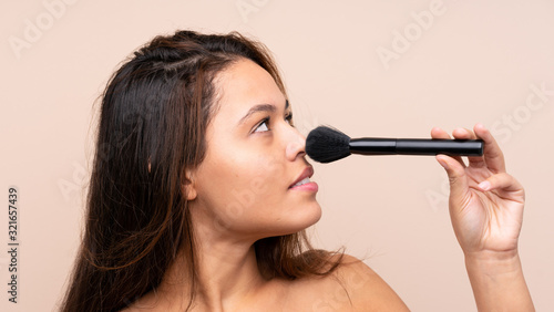 Young Brazilian girl with makeup brush over isolated background