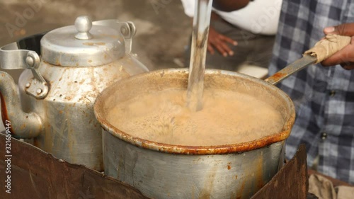Making chai tea on the streets of Mumbai, India. Close up of pan and hands.
