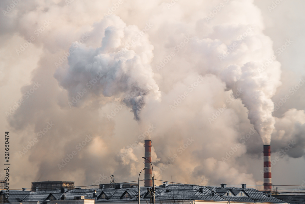 industrial chimneys with heavy smoke causing air pollution on gray sky background