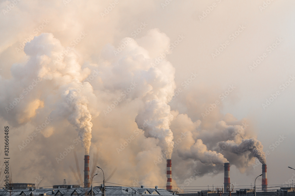 industrial chimneys with heavy smoke causing air pollution on gray sky background