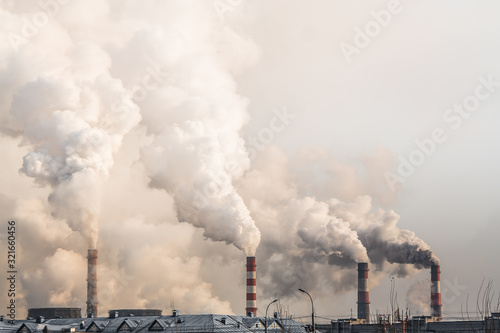 industrial chimneys with heavy smoke causing air pollution on gray sky background