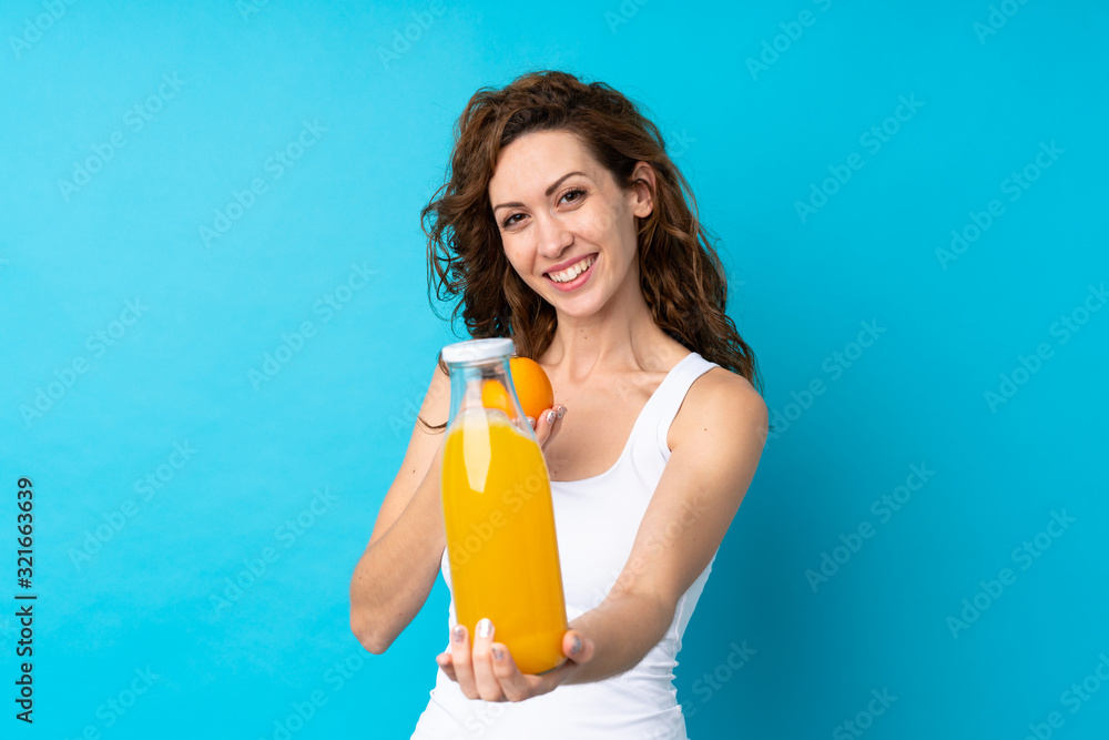 Young woman with curly hair holding an orange over isolated blue background Young woman with curly hair holding an orange over isolated blue background