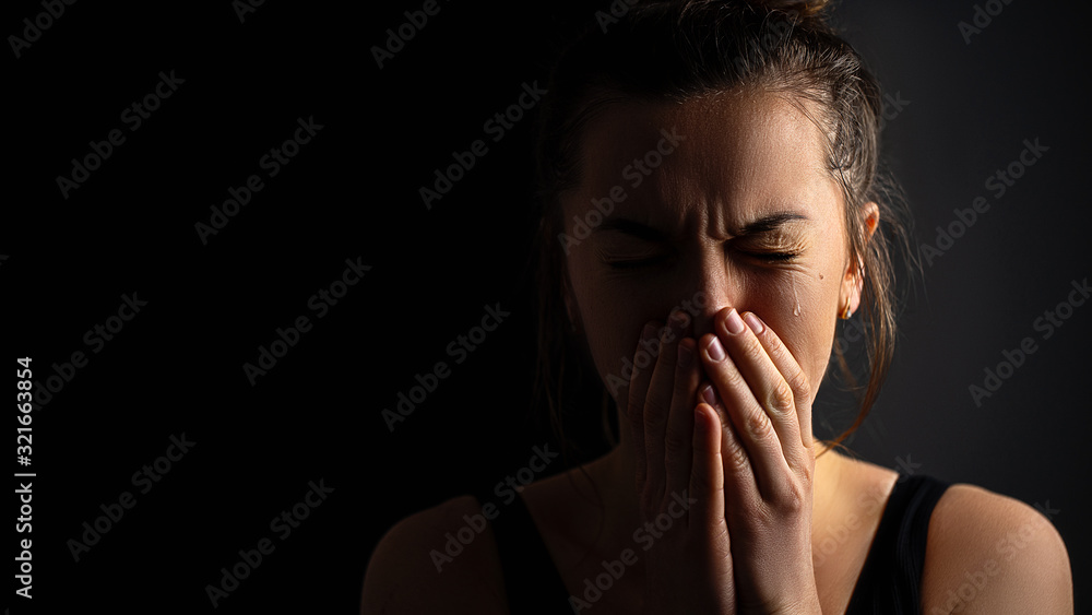 Sad desperate grieving crying woman with folded hands and tears eyes on a dark black background during trouble, life difficulties, loss and emotional problems. Copy space Sad desperate grieving crying woman with folded hands and tears eyes on a dark black background during trouble, life difficulties, loss and emotional problems. Copy space