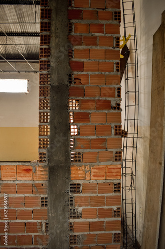 Pilar de concreto armado e parede de alvenaria cerâmica em construção. Tijolo baiano