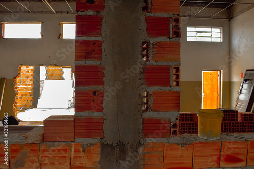 Pilar de concreto armado e parede de alvenaria cerâmica em construção. Tijolo baiano