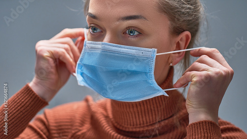 Female putting on medical protective mask to health protection and prevention during flu virus outbreak, epidemic and infectious diseases photo