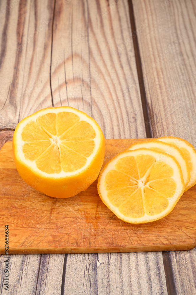 Sliced ripe yellow lemon on a Board on a wooden background. Close up. Sliced ripe yellow lemon on a Board on a wooden background. Close up.
