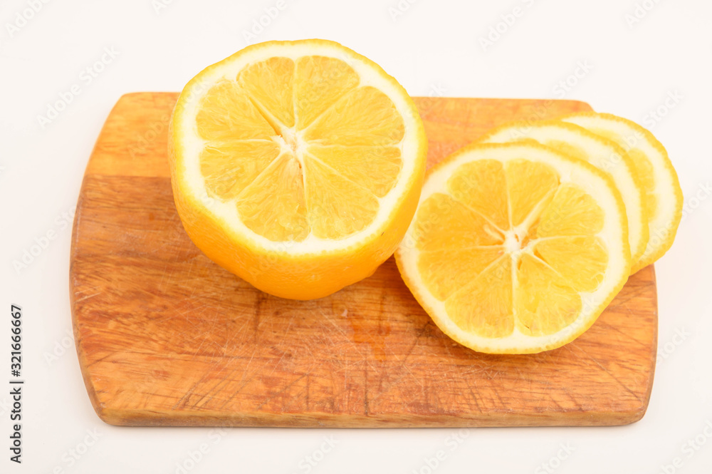 Ripe yellow sliced lemon on a Board on a white background. Close up. Ripe yellow sliced lemon on a Board on a white background. Close up.