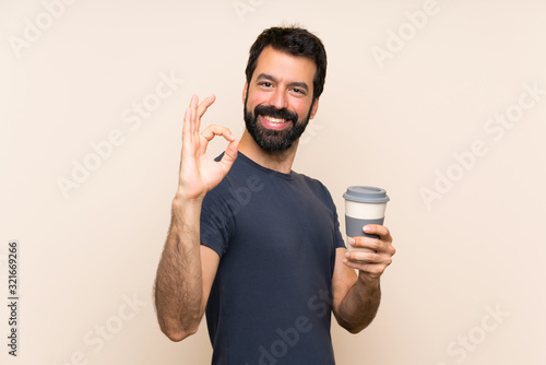Man with beard holding a coffee showing ok sign with fingers