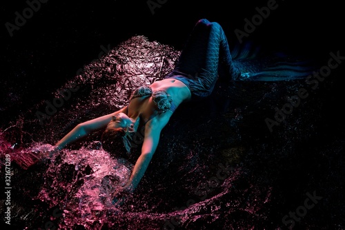 Mermaid splashing in water under pink light photo