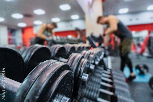 Close-up dumbbells on blurred background of a bodybuilder. Gym concept.