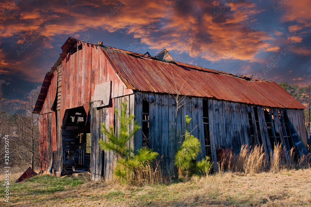 An old barn with a rusty roof in a rural area An old barn with a rusty roof in a rural area