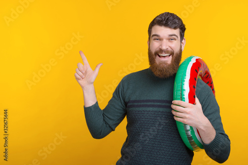 Photo of joyful worker holding swiming circle and pointing away photo