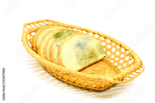 several slices of bread covered with mold lie in a basket isolated on a white background