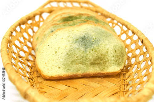several slices of bread covered with mold lie in a basket isolated on a white background