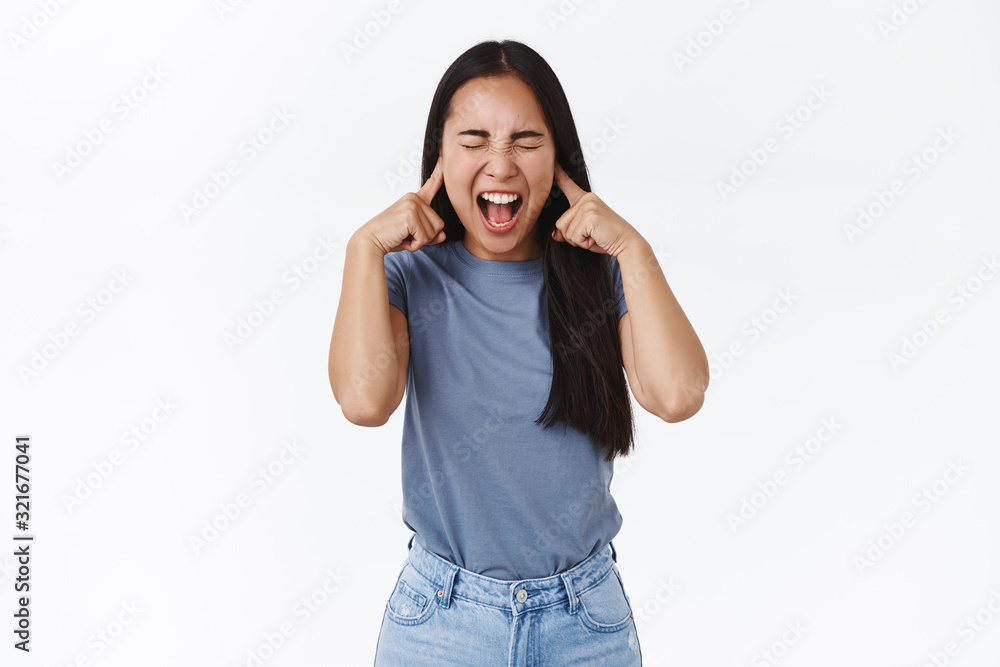 Distressed and fed up asian teenage girl with long dark hair, screaming losing temper, cant control emotions, close eyes and yelling, close ears with fingers cant stand people fighting around her Distressed and fed up asian teenage girl with long dark hair, screaming losing temper, cant control emotions, close eyes and yelling, close ears with fingers cant stand people fighting around her